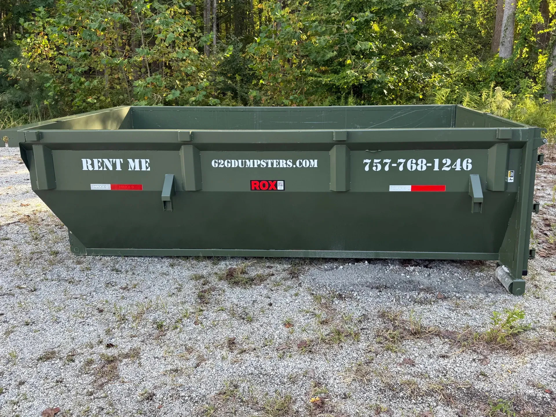 A dog is standing in front of a dumpster.