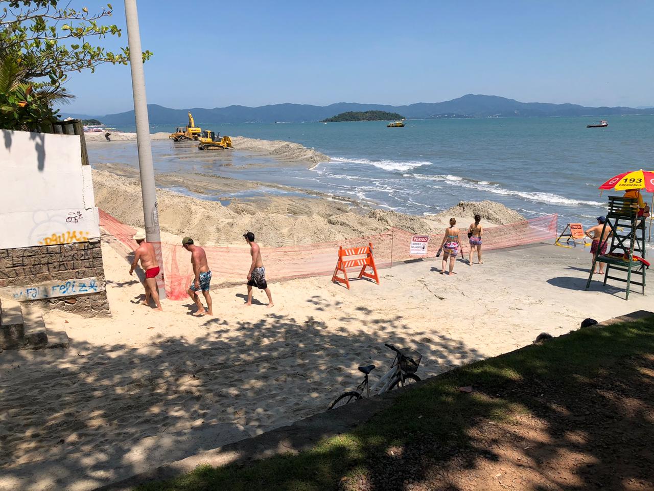 Um grupo de pessoas caminha em uma praia perto do oceano.