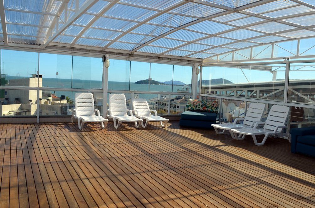 Um deck com cadeiras e teto transparente com vista para o mar