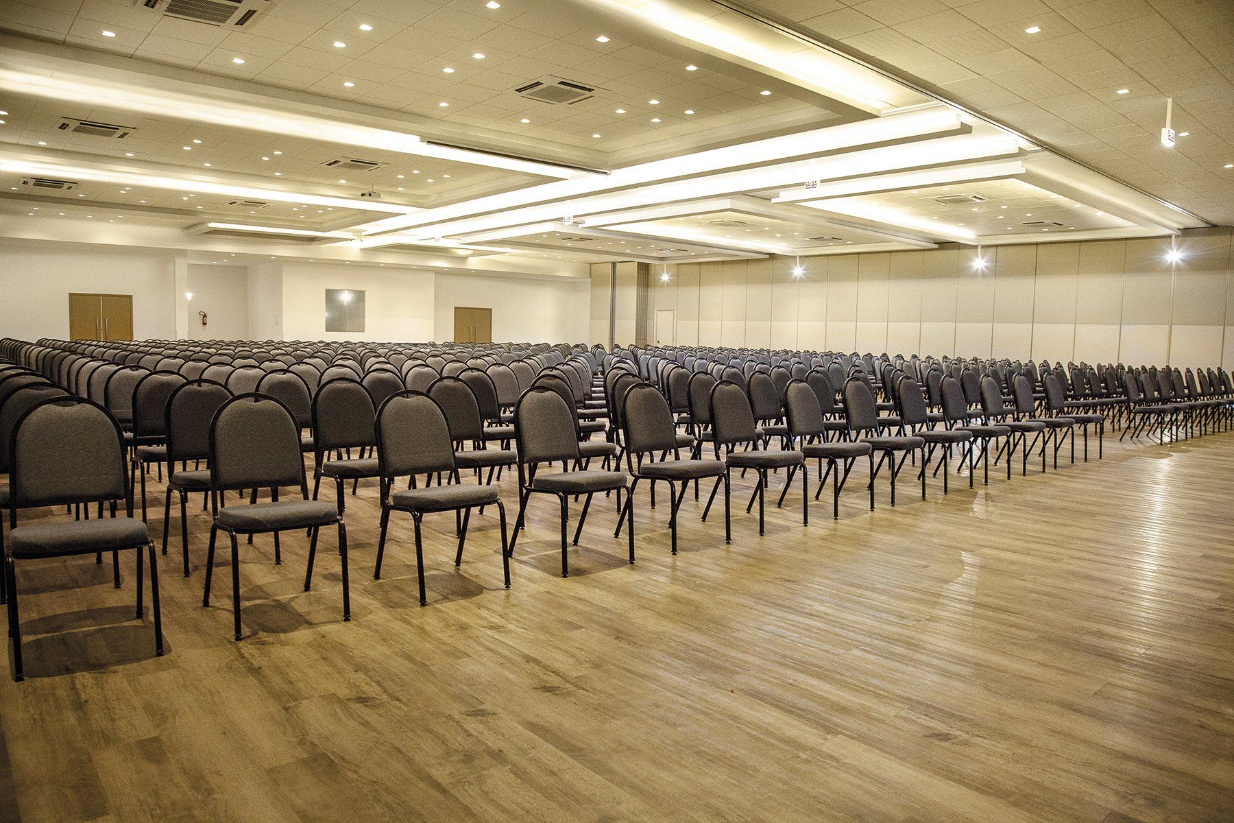 Fileiras de cadeiras estão alinhadas em uma grande sala.