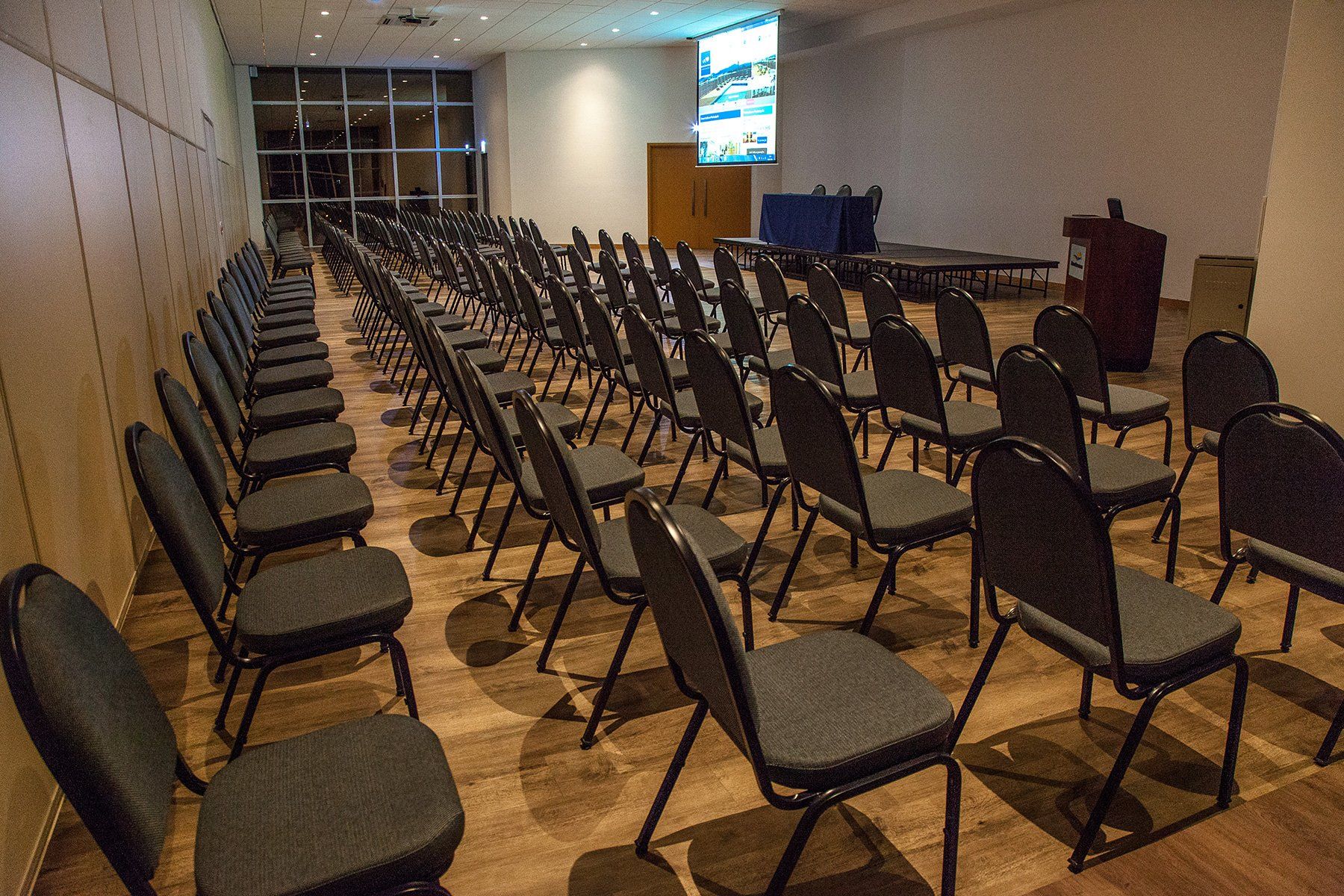 Uma sala de conferências com fileiras de cadeiras e uma tela de projeção.