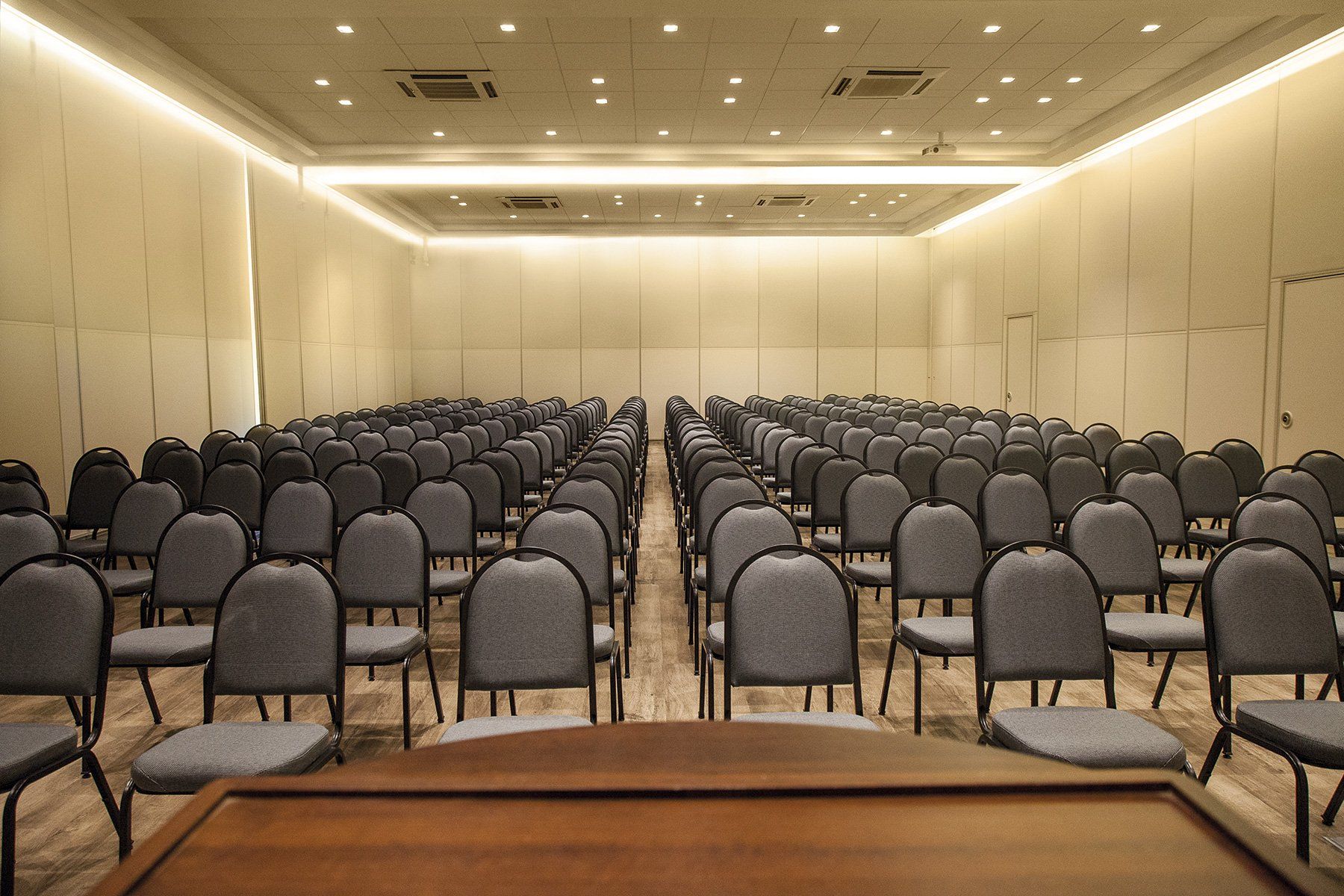 Uma grande sala de conferências com fileiras de cadeiras e um pódio no meio.