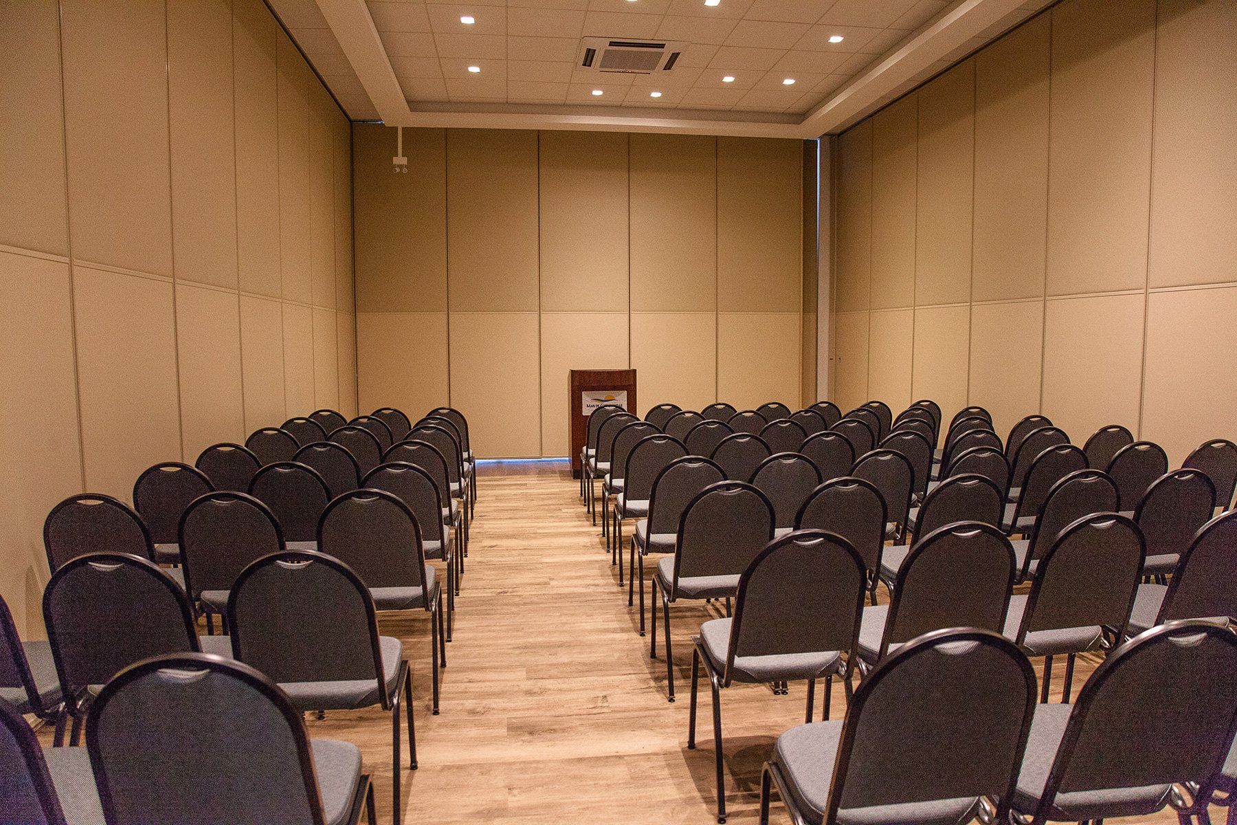 Uma sala de conferências com fileiras de cadeiras e um pódio.