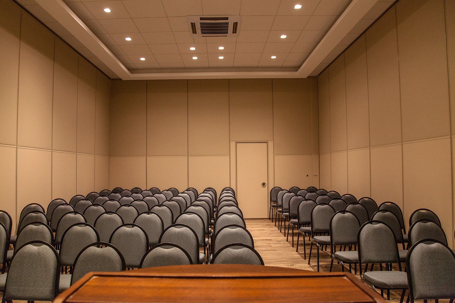 Uma sala de conferências com fileiras de cadeiras e um pódio no meio.