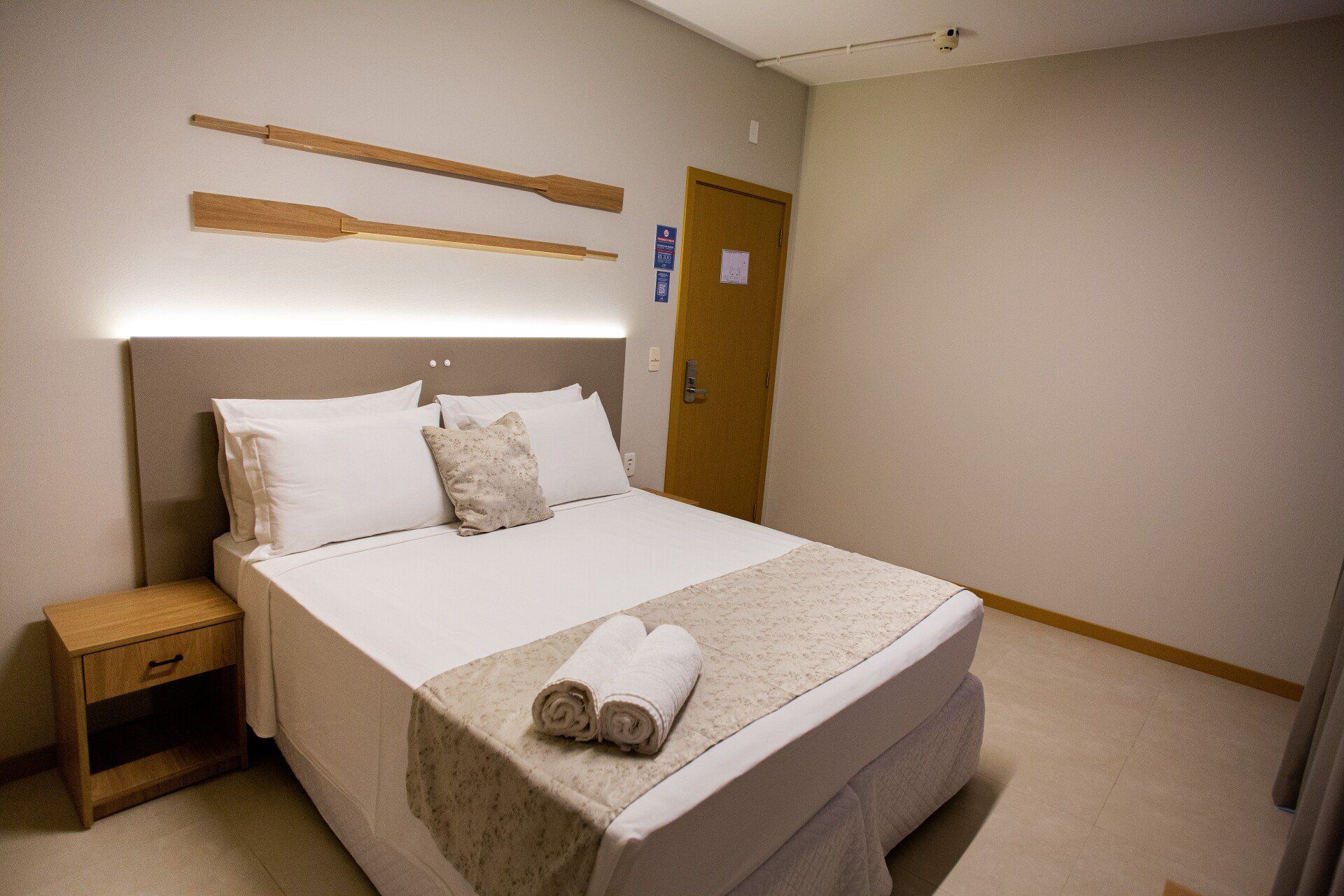 Um quarto de hotel com cama, mesa de cabeceira e porta.