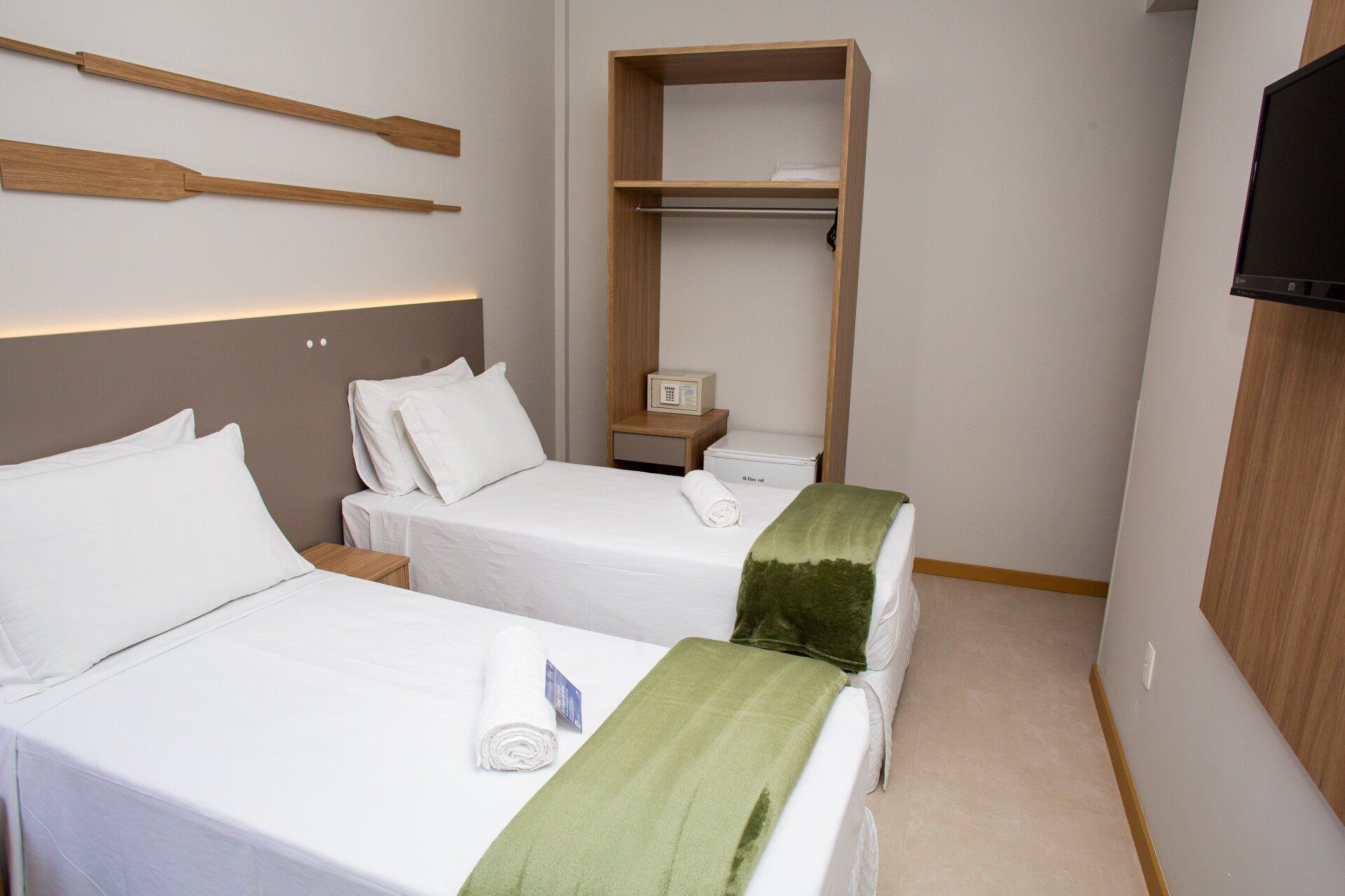 Um quarto de hotel com duas camas e uma televisão.