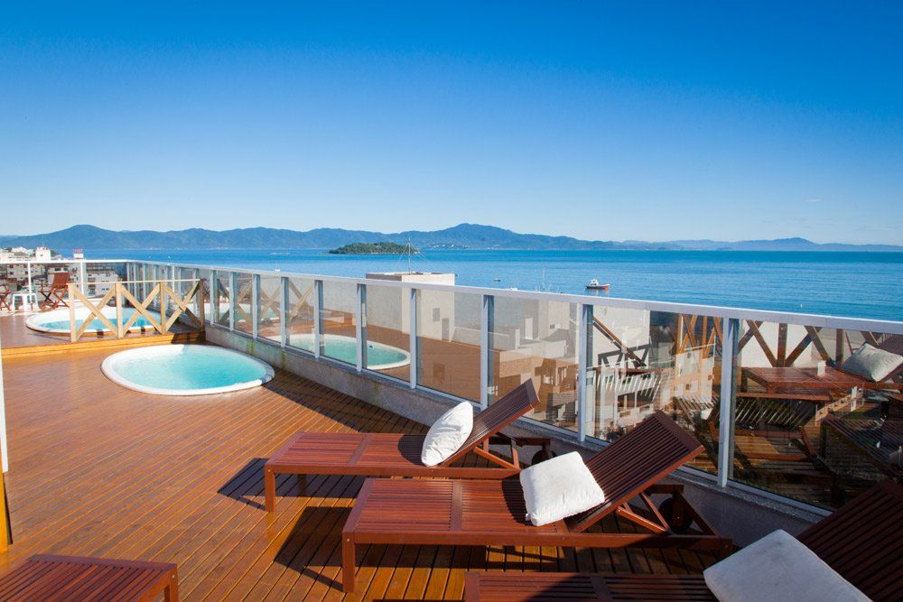 Um deck com cadeiras e uma piscina com vista para o mar