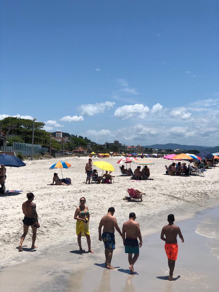 Um grupo de homens caminha pela praia de mãos dadas.