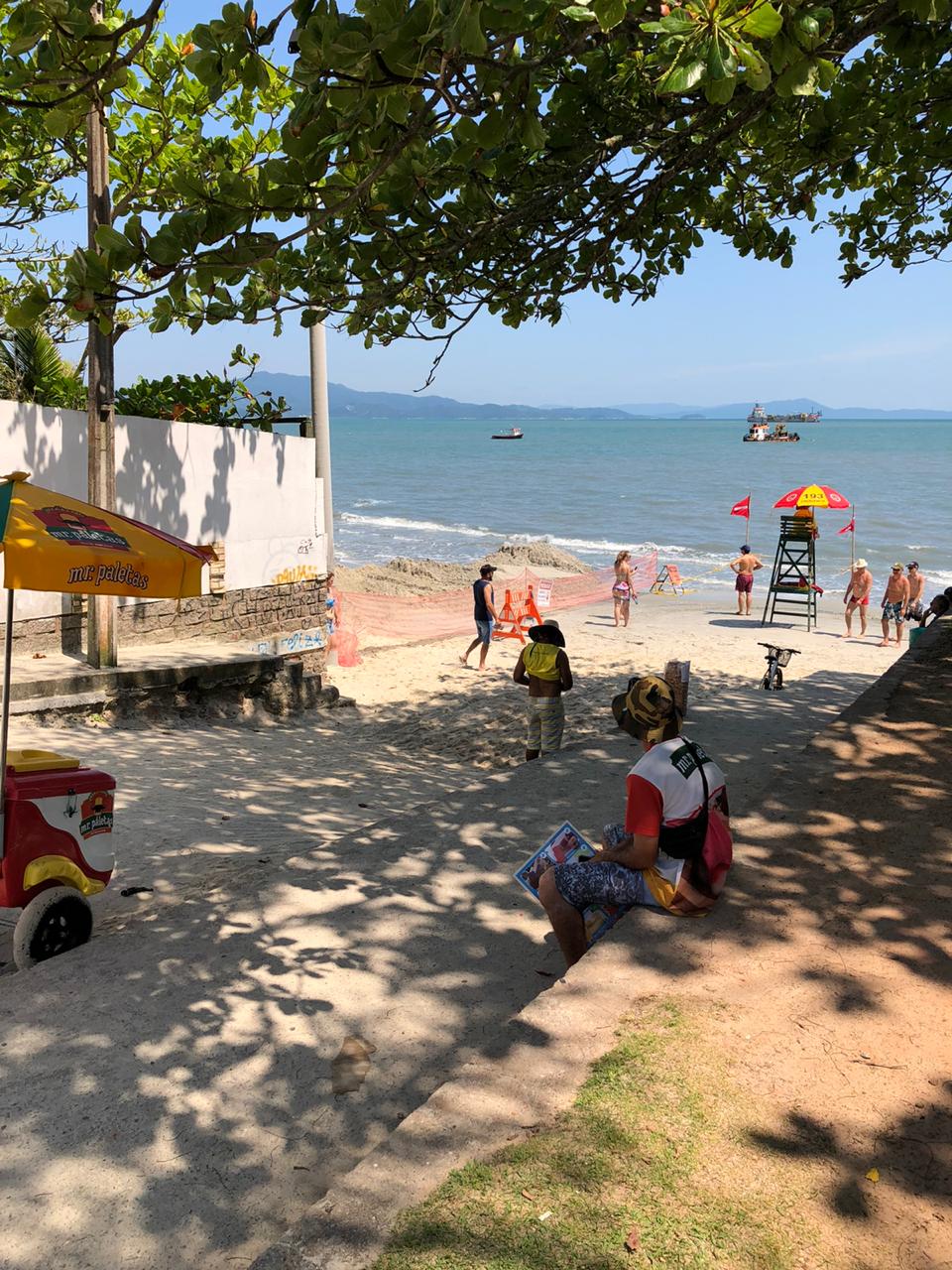 Um grupo de pessoas está sentado na praia olhando para o mar.