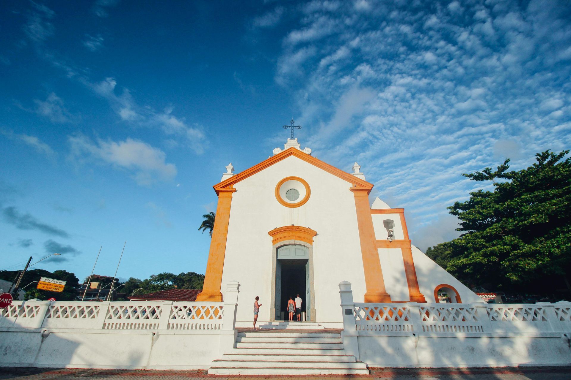 Uma igreja branca e laranja com um céu azul ao fundo.