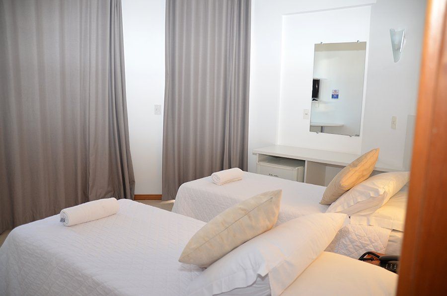 Um quarto de hotel com duas camas e um espelho.
