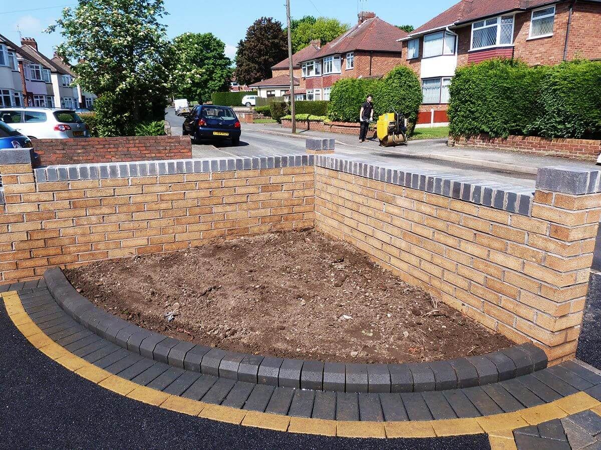 A car is parked in front of a brick wall