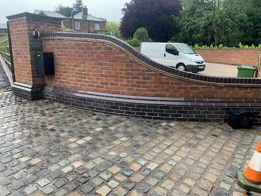 A white van is parked in front of a brick wall.