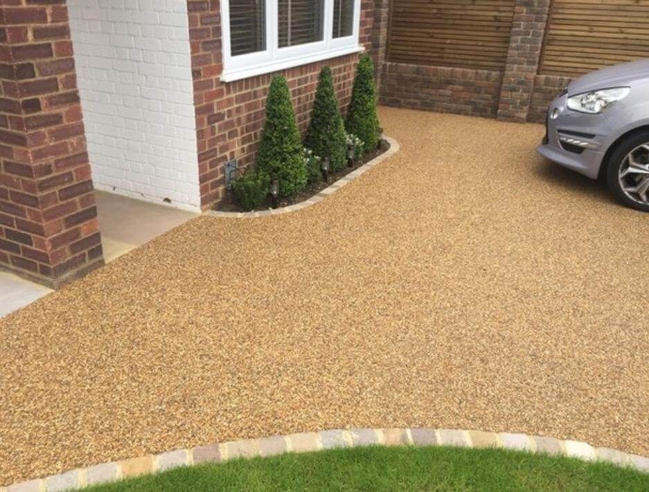 A car is parked in a driveway next to a brick house.