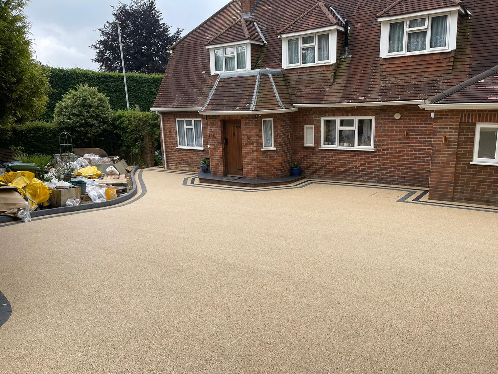 A large brick house with a gravel driveway in front of it.