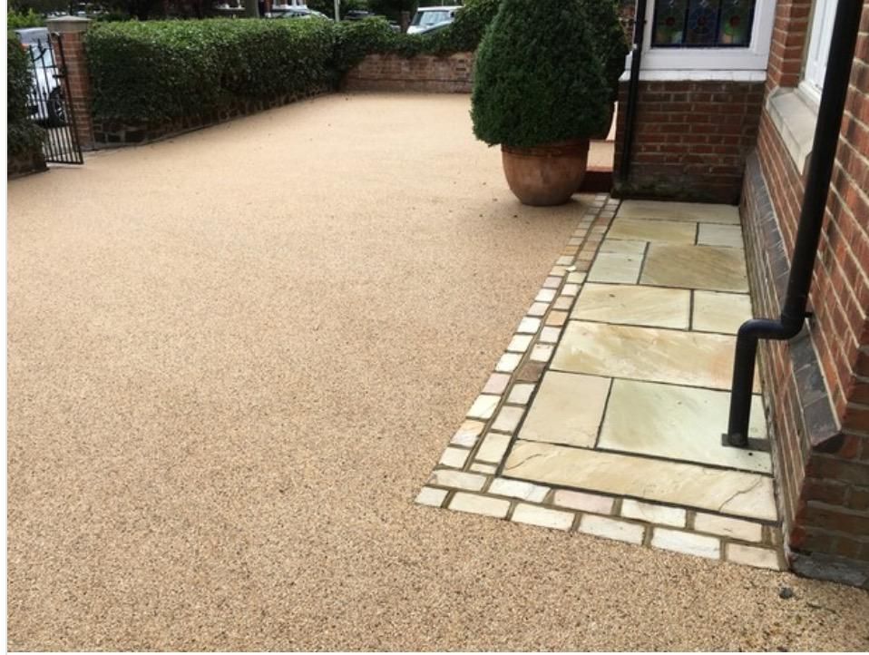 A driveway with a brick walkway and a drainpipe next to a brick building.