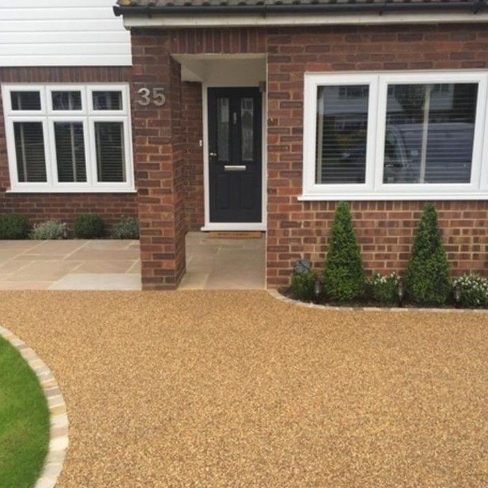 A brick house with a gravel driveway in front of it.