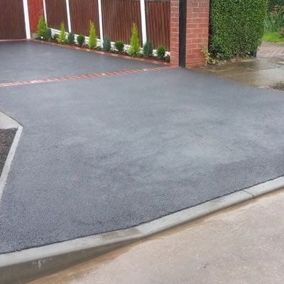 A black tarmac driveway with a brick fence in the background.