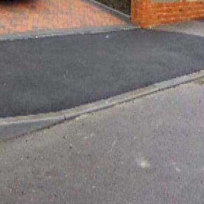 A close up of a road with a brick wall in the background.