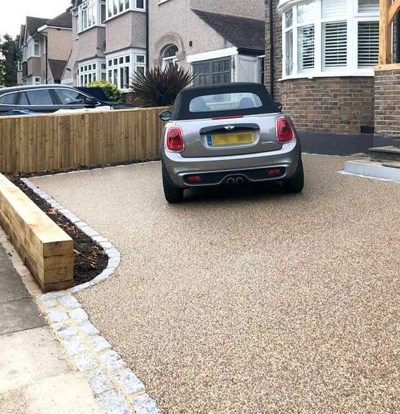 A silver car is parked in a driveway in front of a house.