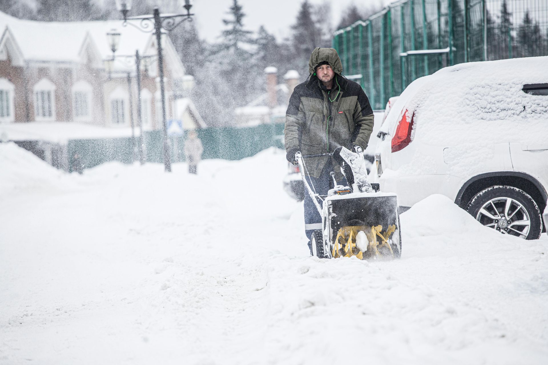 Snow blower in action on a driveway in snowy conditions
