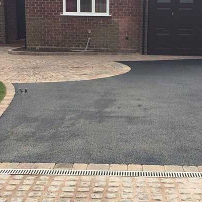 A driveway with a drainage system in front of a brick house.