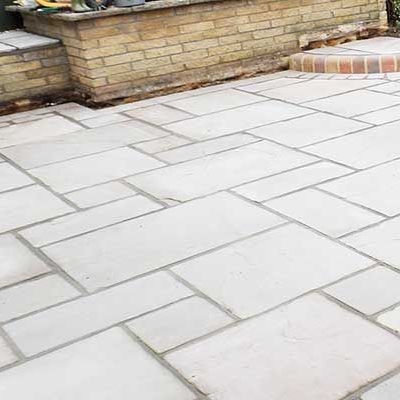 A patio with white tiles and a brick wall in the background.