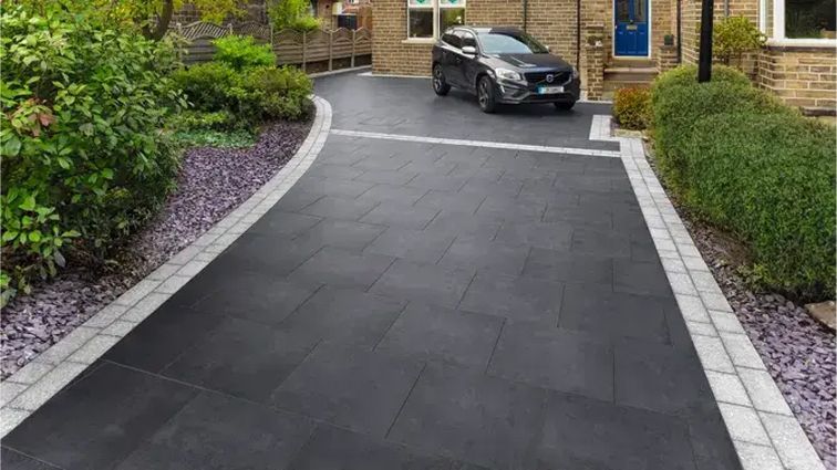 A car is parked in a driveway next to a house.