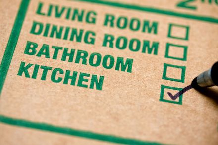Checklist with green rooms listed and a pen marking the kitchen box