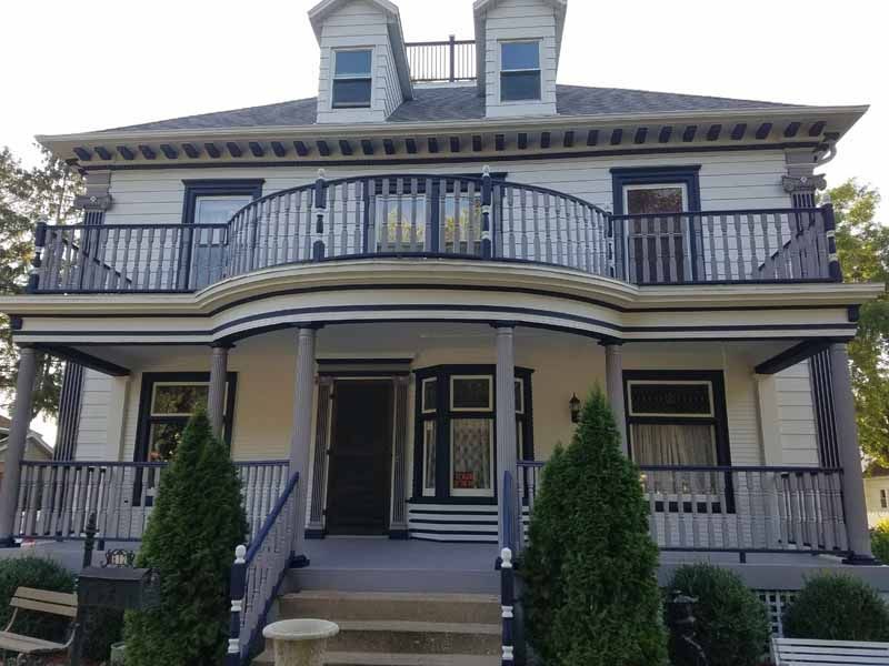 A large white house with a balcony and stairs