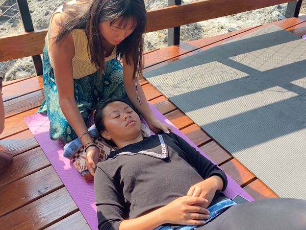 A woman is laying on a yoga mat with her eyes closed