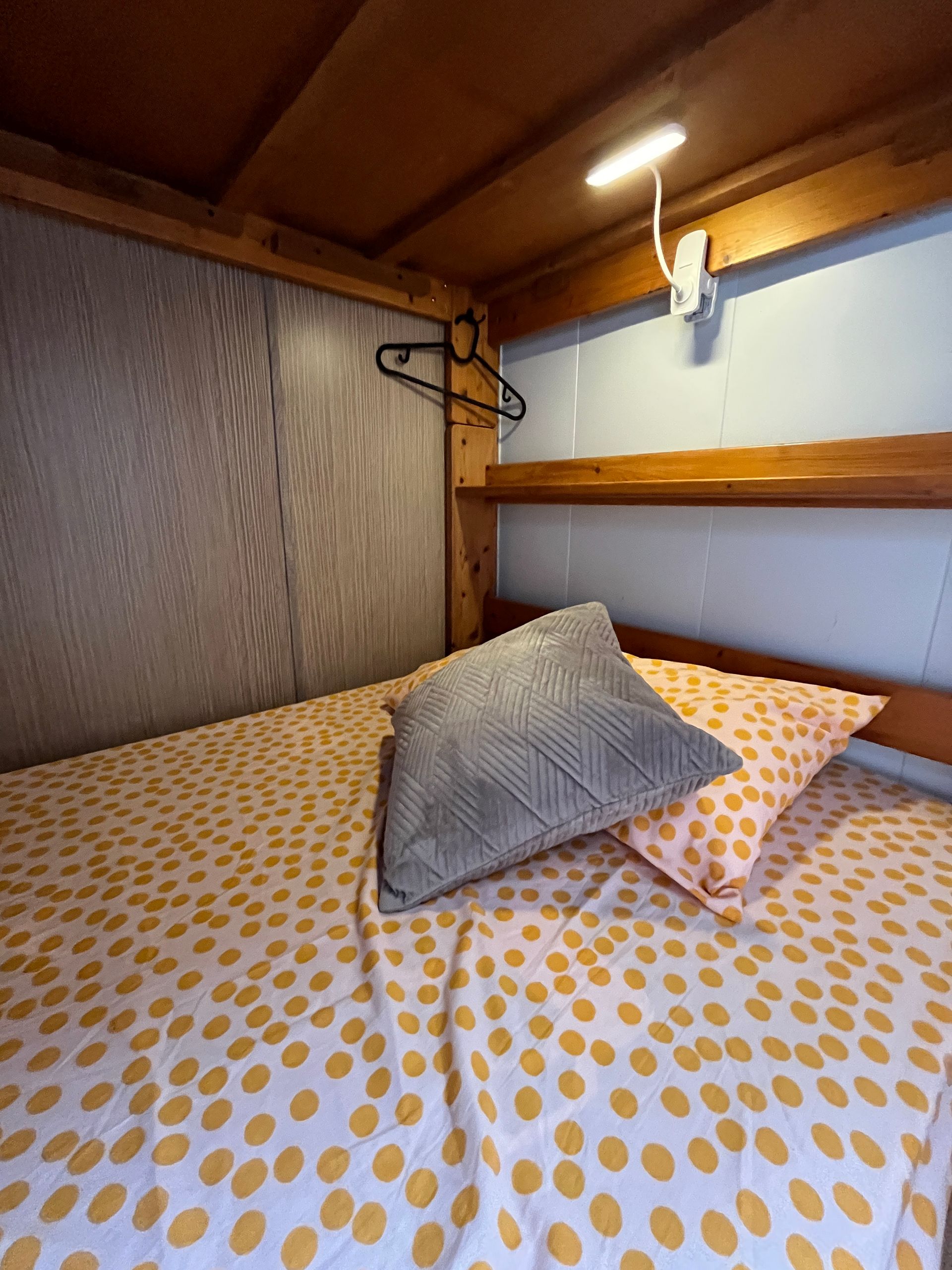 A bunk bed with two pillows and a hanger on the wall.