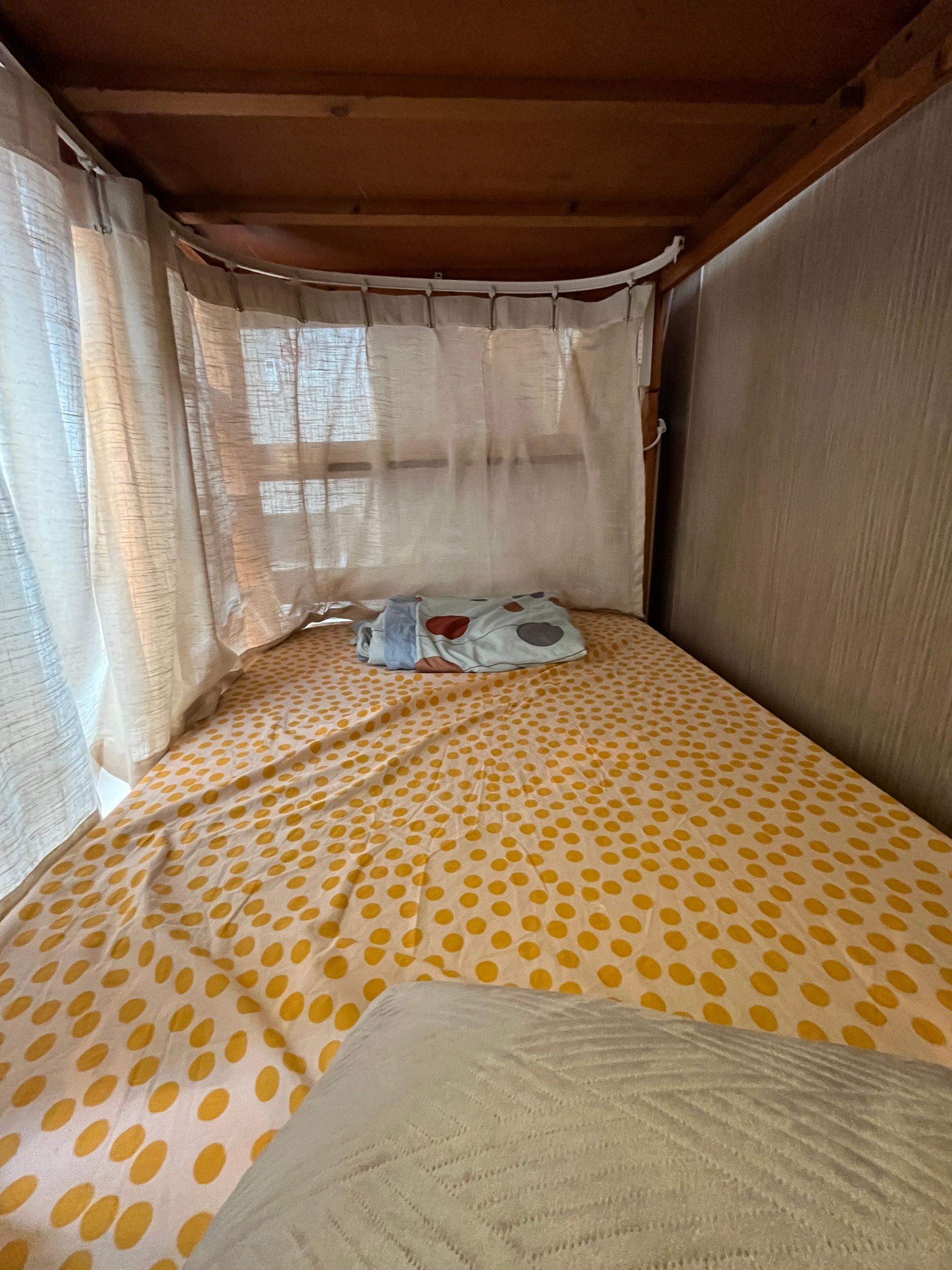 A bunk bed with a yellow polka dot blanket and a window.