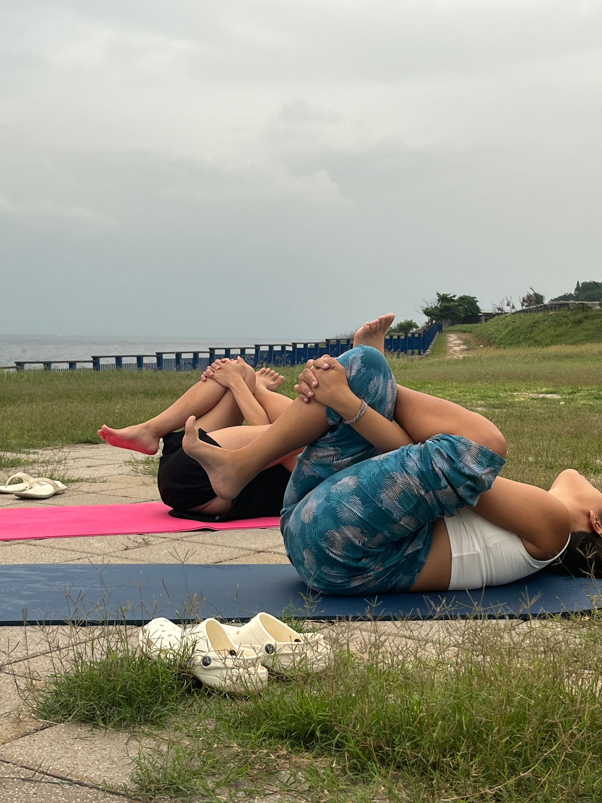 A couple of people are laying on a yoga mat in a field.