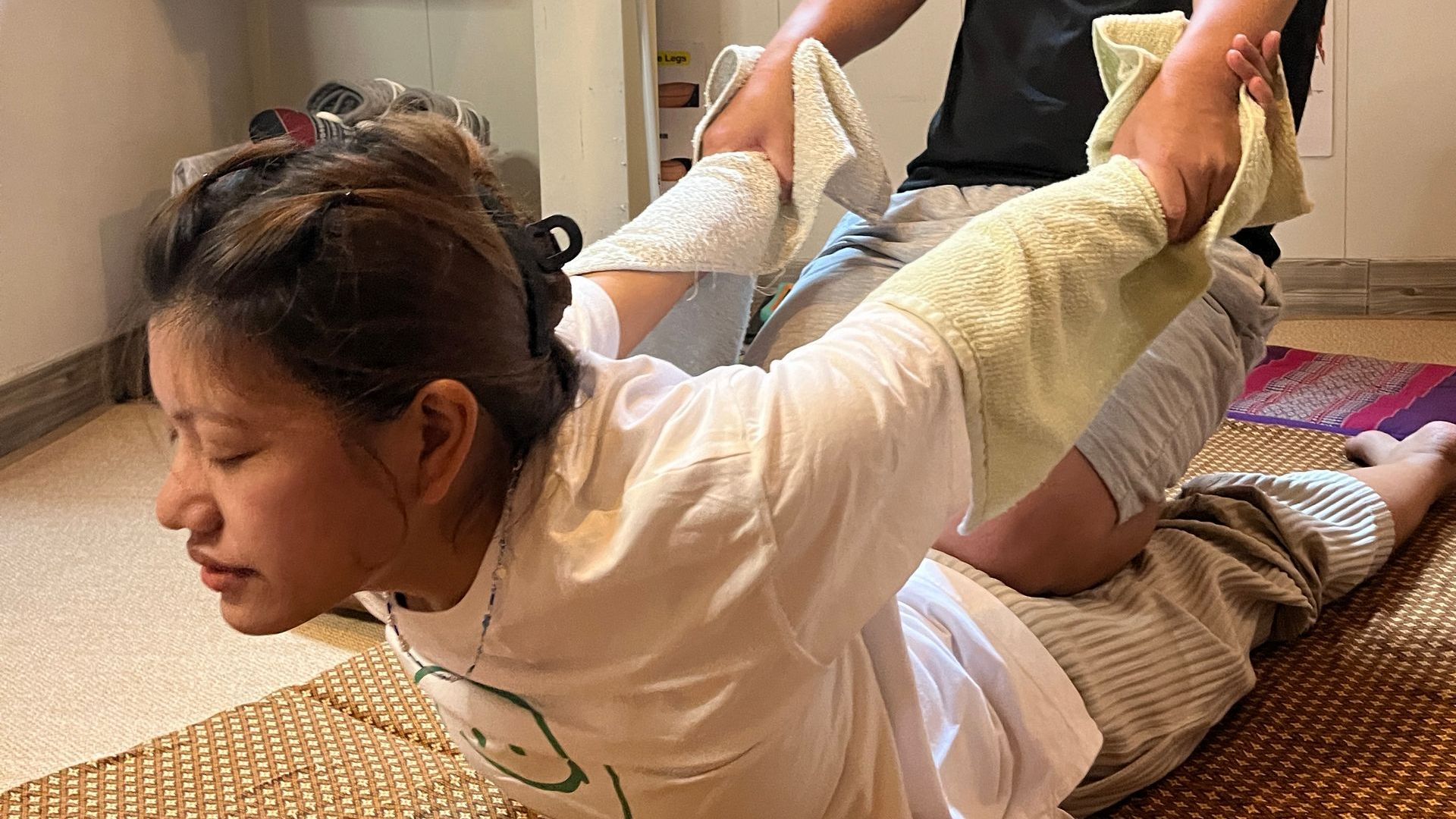 A woman is laying on the floor getting a massage from a man.