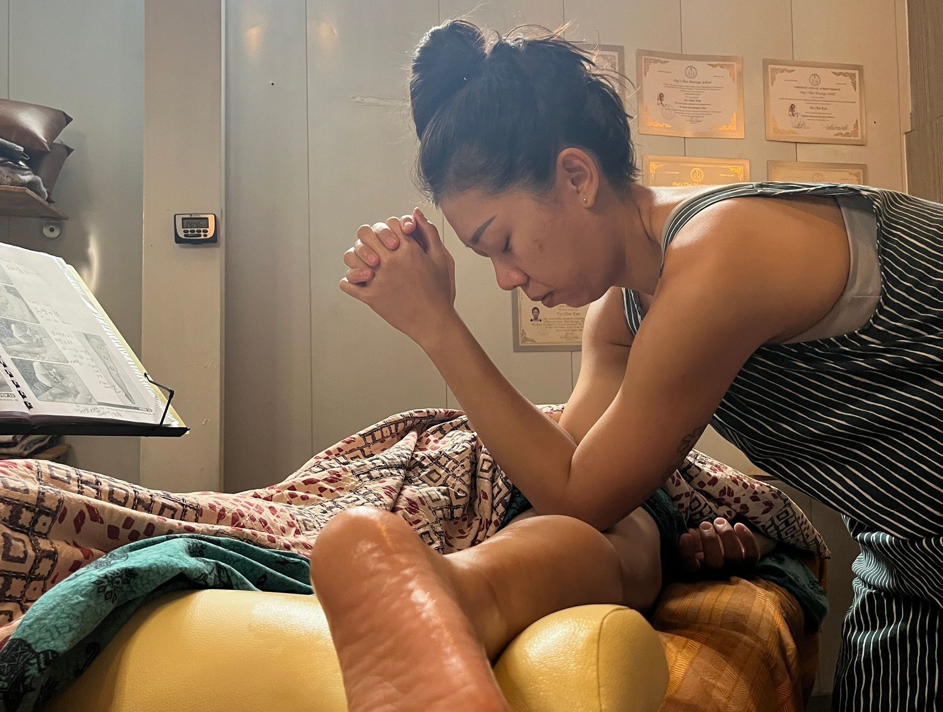 A woman is praying over a person 's foot while laying on a bed.