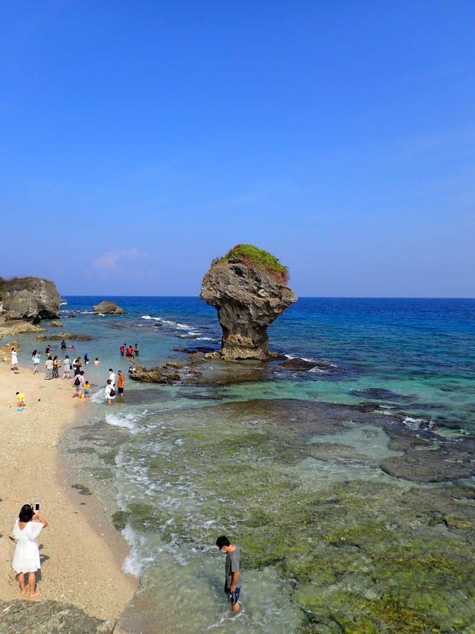 A group of people are standing on a beach near the ocean.