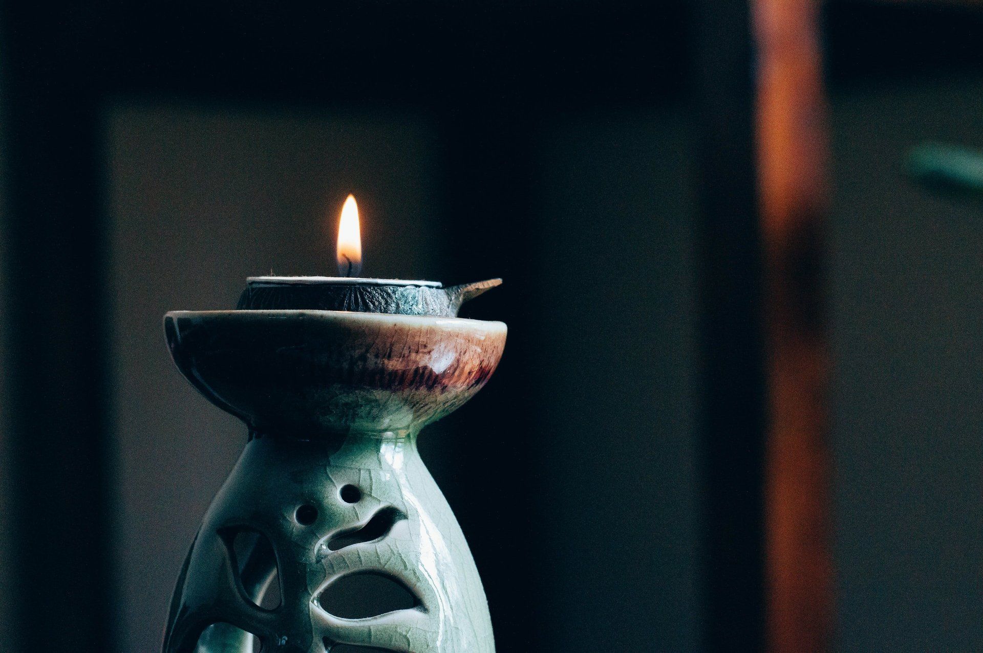 A close up of a candle in a candle holder on a table.