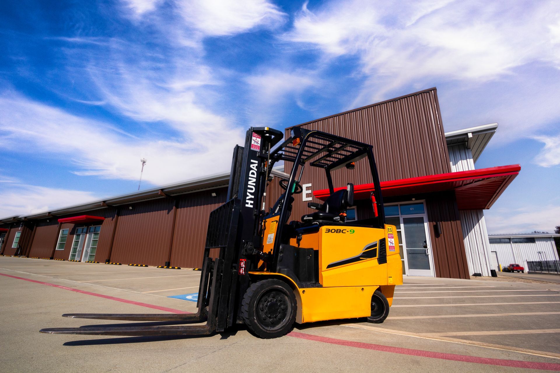 A yellow forklift is parked in front of a building.