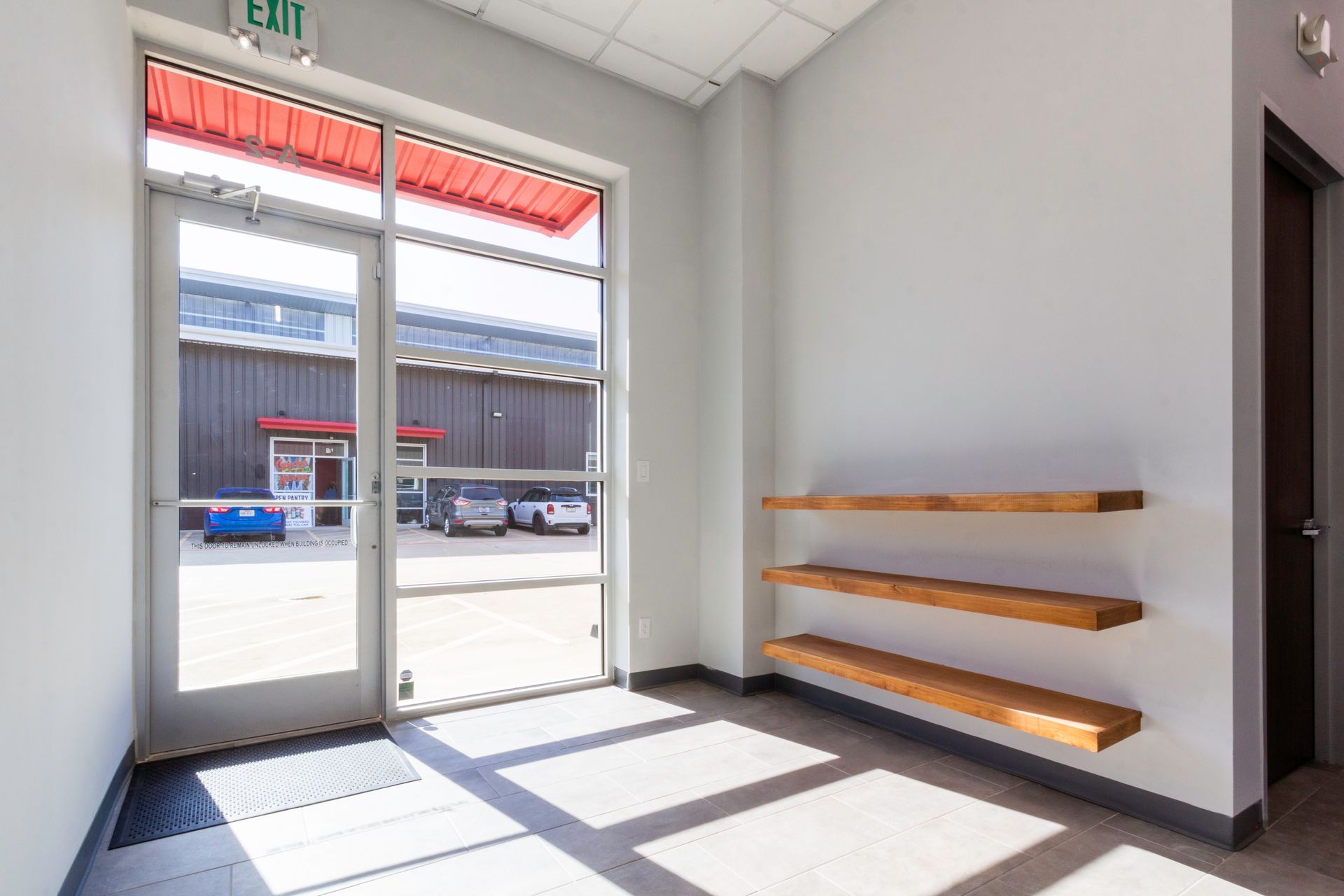 An empty room with a green exit sign on the wall.