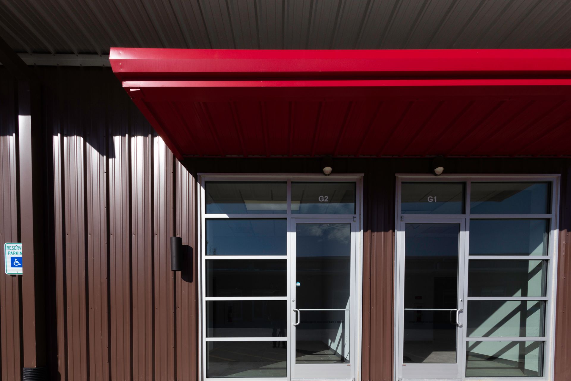 A brown building with a red awning over the doors