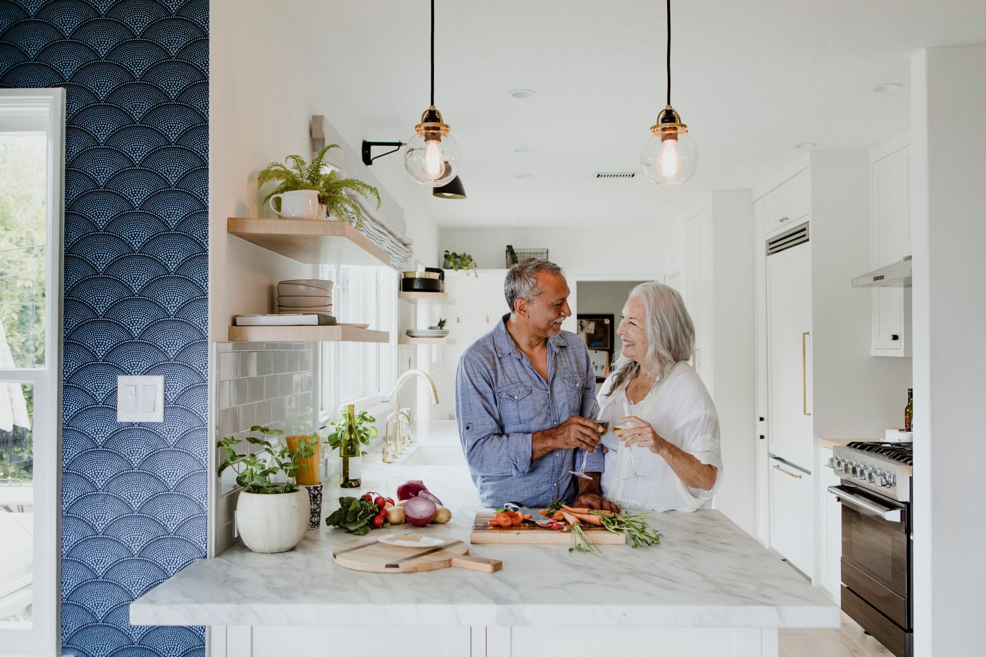 A mature couple in a newly renovated modern kitchen with a large marble island.