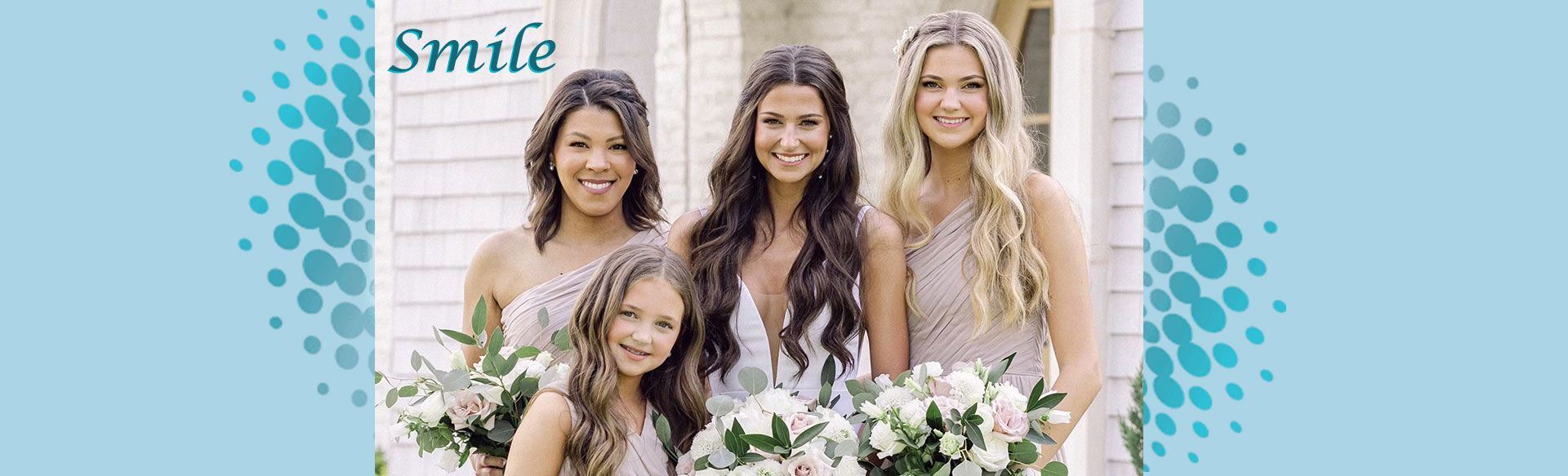 Group of smiling women with child in light-colored dresses, holding bouquets, with a light blue background.