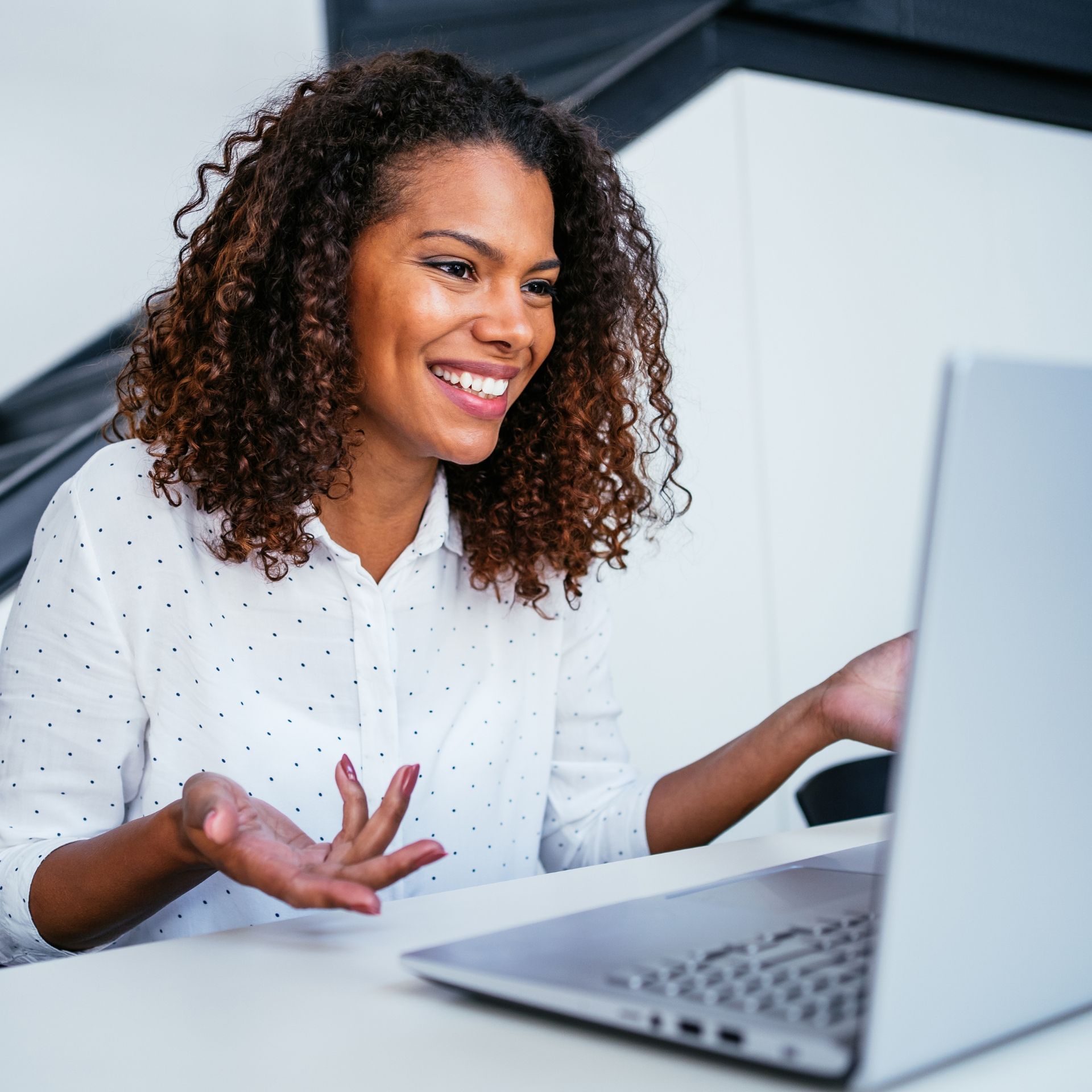 A woman is smiling while using a laptop computer.