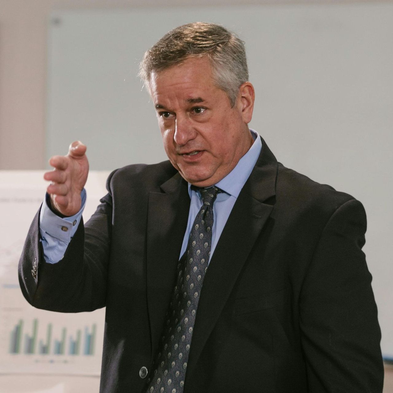 A man in a suit and tie is pointing at something