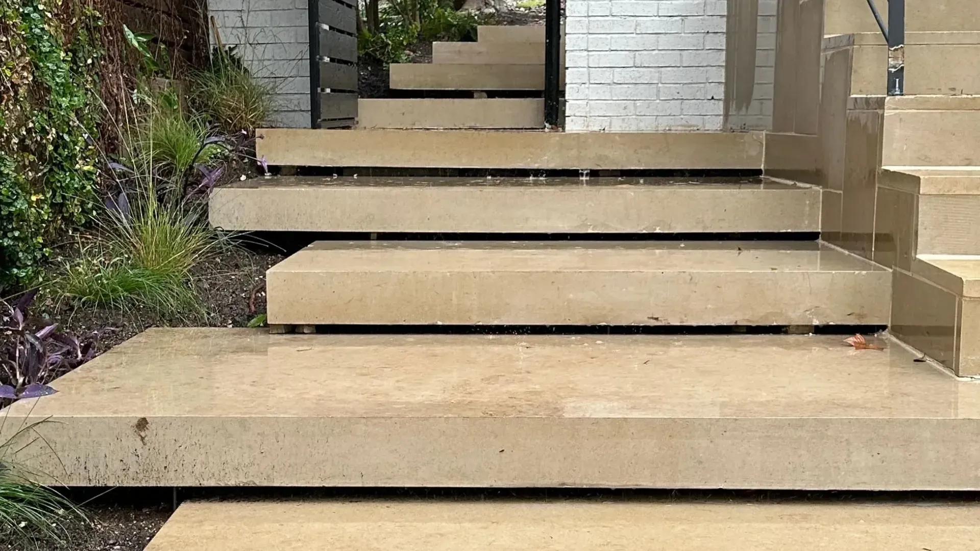 Concrete steps leading up, with black metal railing.