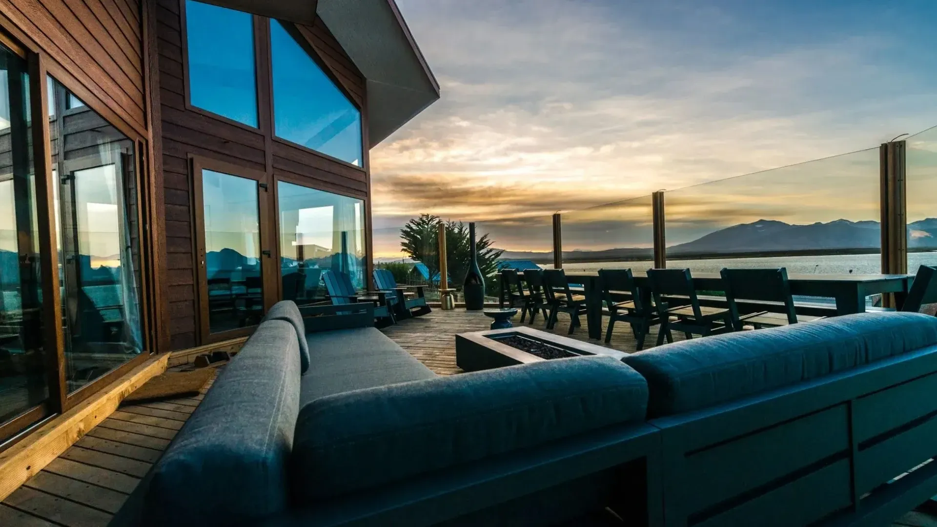 Outdoor deck with modern furniture overlooking a body of water at sunset.