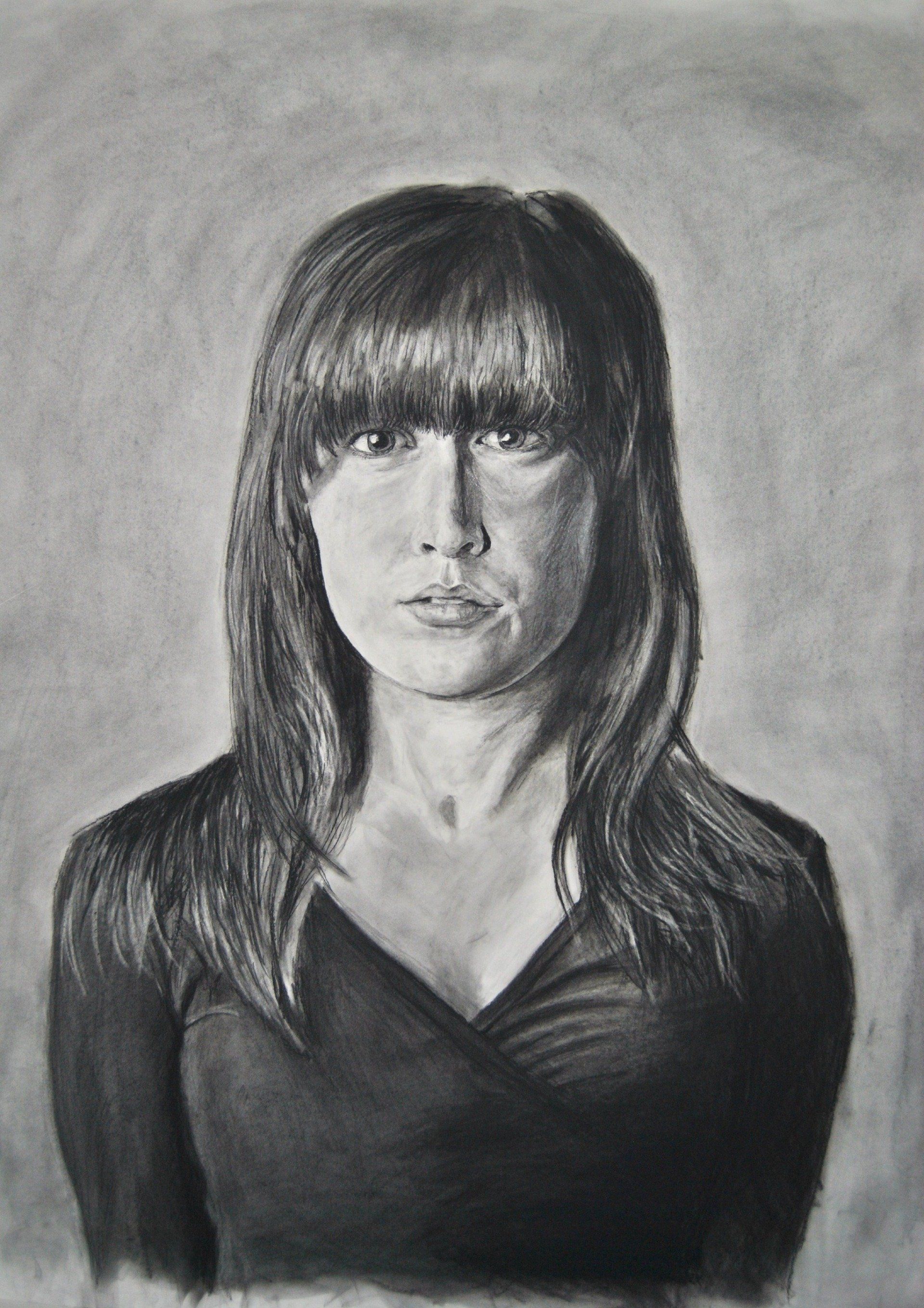 Charcoal portrait of a person with long hair and bangs, wearing a dark top, looking directly at the viewer.