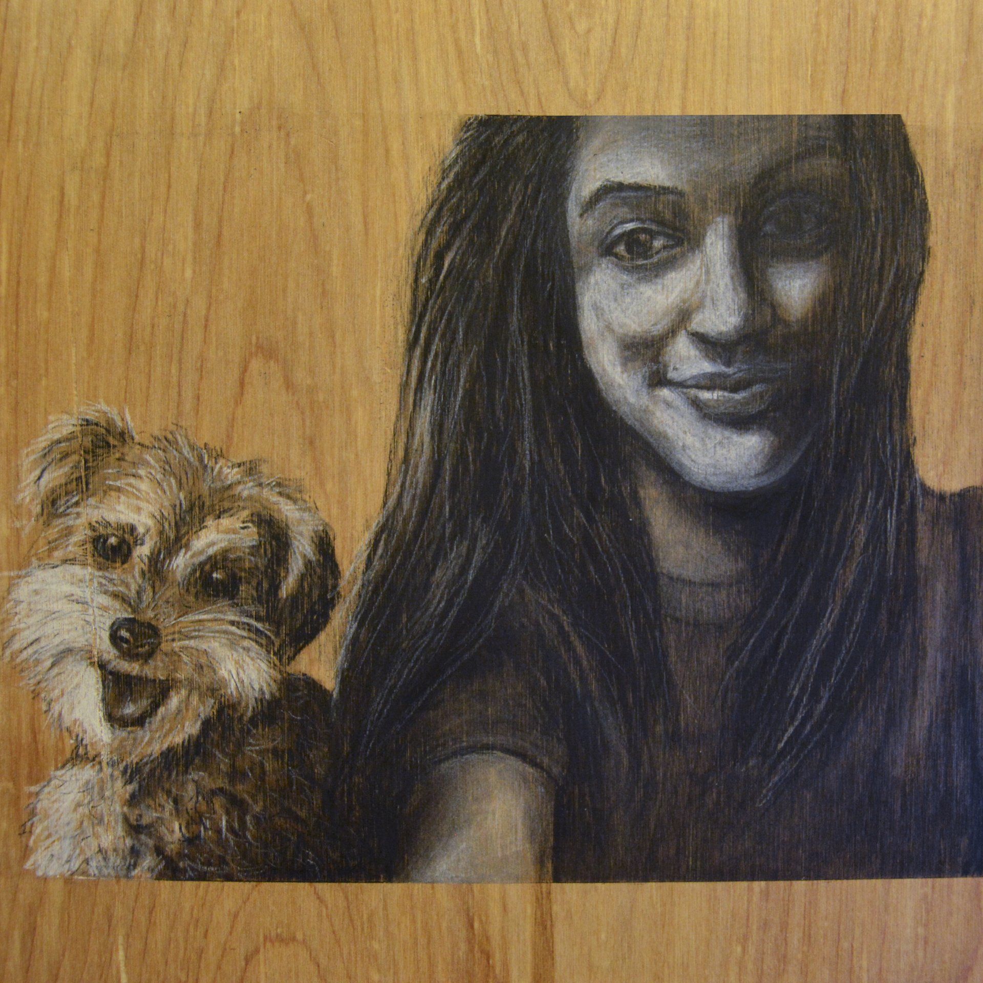 Woman smiles taking selfie with small, happy dog; charcoal sketch on wood.
