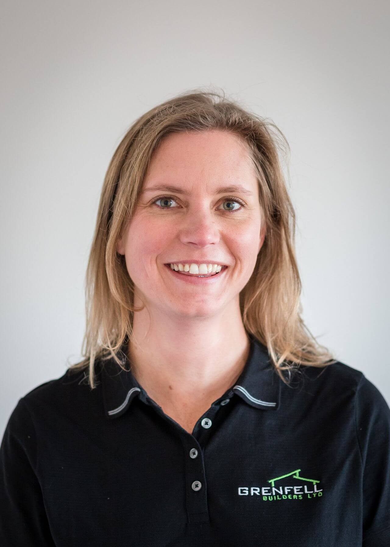 a woman wearing a black polo shirt is smiling for the camera .